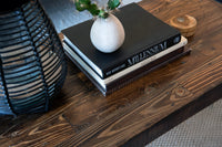 This handcrafted reclaimed wood table, made in Arizona, showcases enduring quality and sustainable craftsmanship. Topped with curated books, a desert cactus in a round vase, and a woven lantern for inviting warmth.
