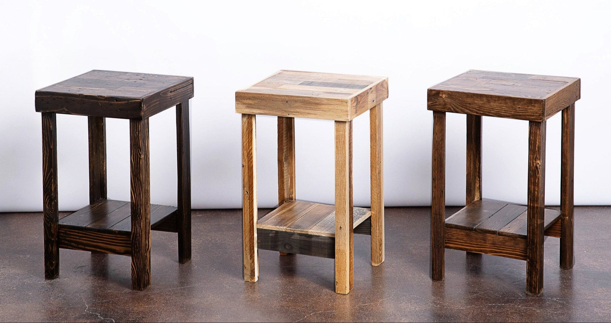 Three handcrafted wooden side tables with square tops and lower shelves, featuring two dark-stained tables flanking a light natural wood table; ideal for historic homes or modern minimalist spaces.