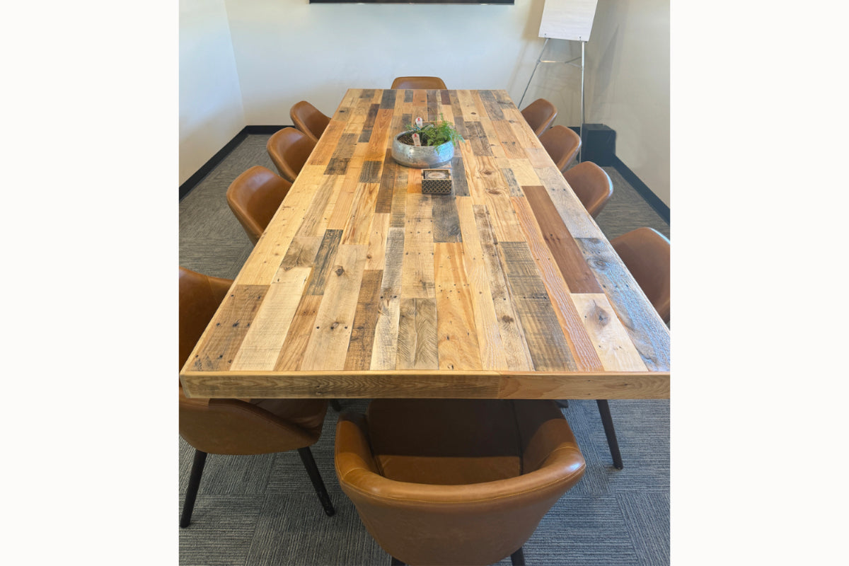 This handcrafted rectangular conference table, made from sustainable reclaimed wood and featuring a striking centerpiece, is paired with eight brown leather chairs—perfect as a statement restaurant table or office meeting centerpiece.