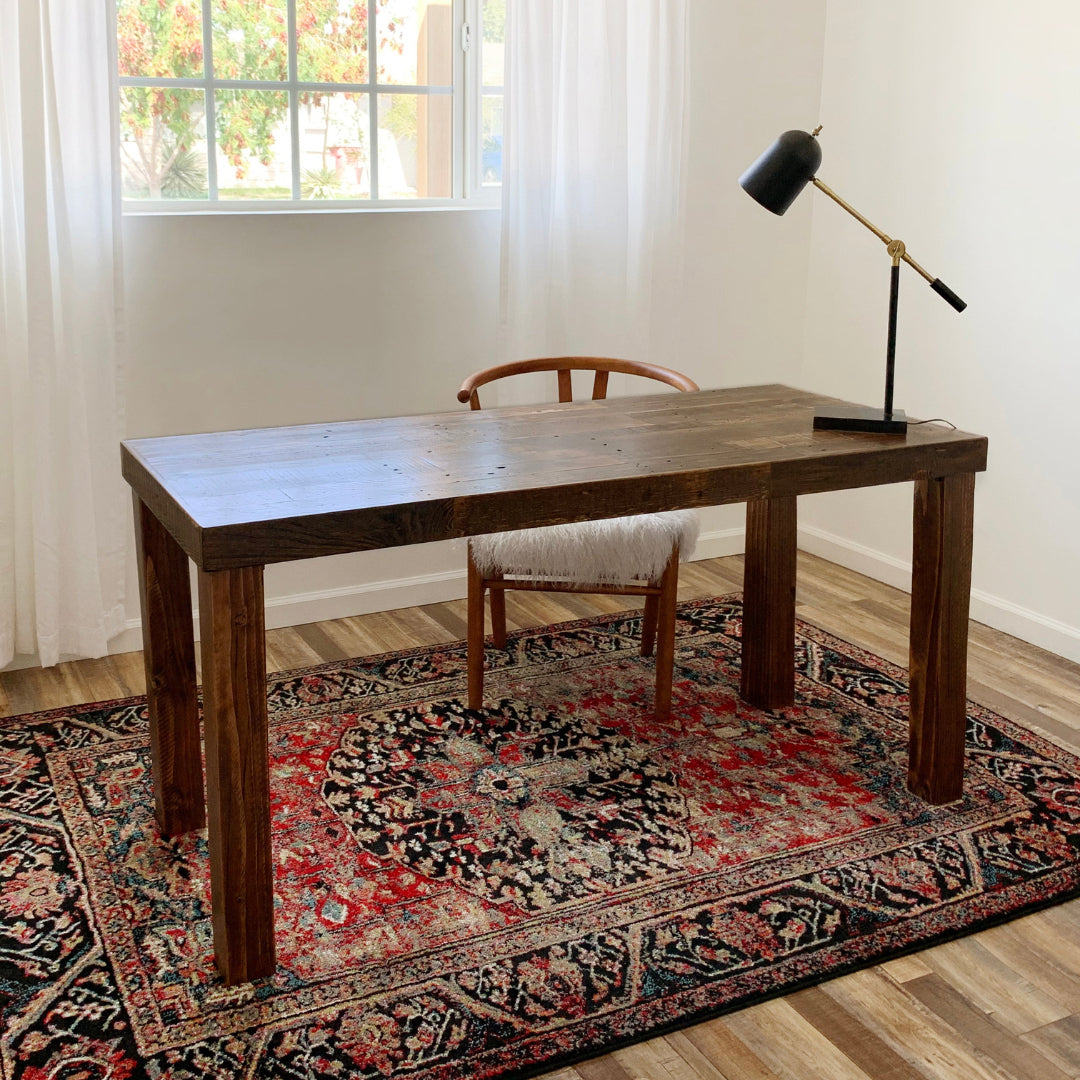 Experience enduring quality with this handcrafted reclaimed wood desk, expertly made in Arizona. Set on a red patterned rug in a sunlit room, it features sustainable materials and classic design—perfect as a narrow table or home office workspace.