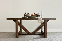 Handcrafted in Arizona, this reclaimed wood farmhouse dining table embodies enduring quality. The dark finish highlights expert craftsmanship, accented by autumnal décor and a light cloth, perfect for home or restaurant settings.