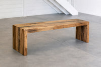 Modern reclaimed wood bench on a concrete floor with a white wall background