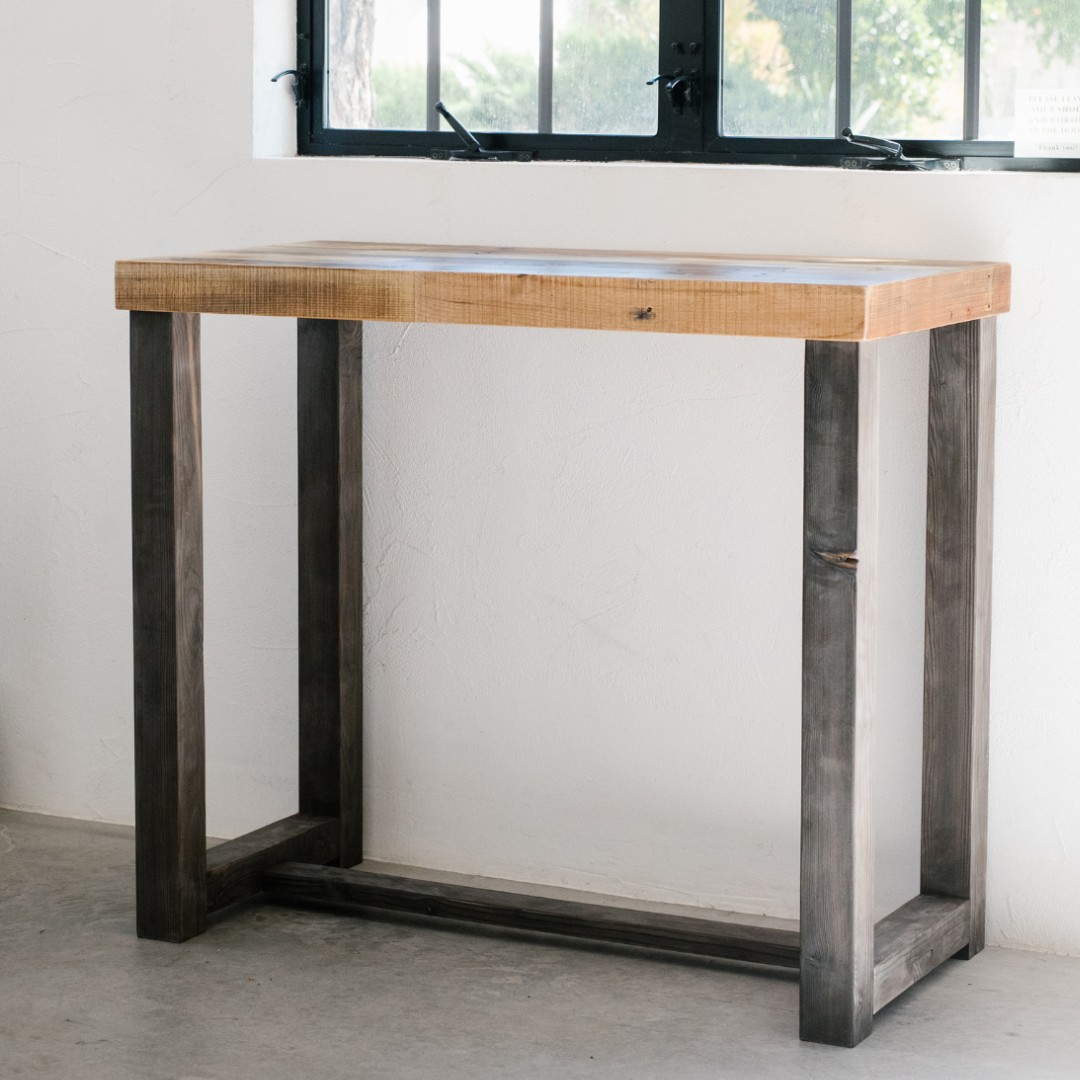 high quality handcrafted bar height wood tables in three different finish colors, photographed in a modern barn with raw concrete flooring and white wood-paneled walls, showcasing Kase Custom's bestselling Sequoia wood high top table