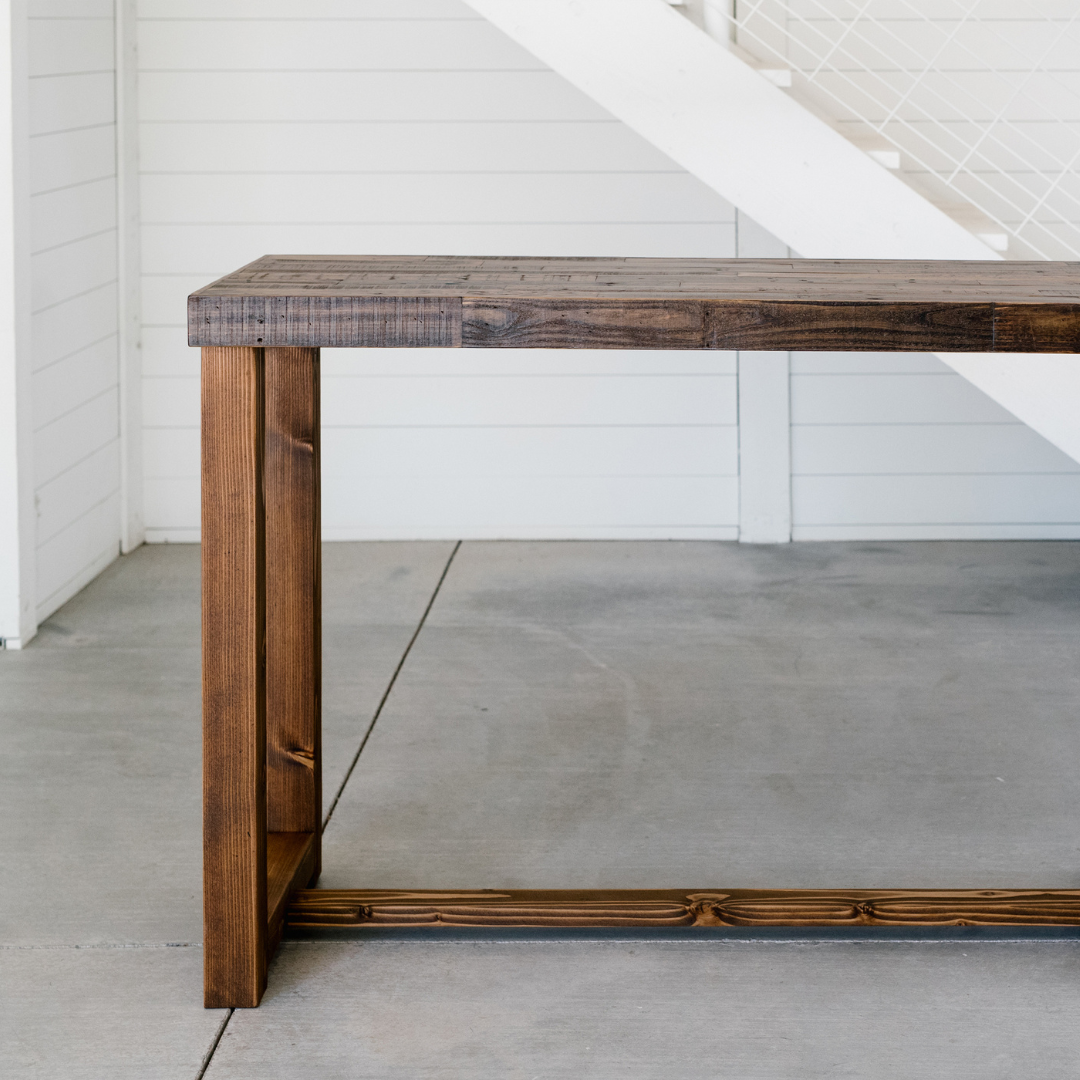 high quality handcrafted bar height wood tables in three different finish colors, photographed in a modern barn with raw concrete flooring and white wood-paneled walls, showcasing Kase Custom's bestselling Sequoia wood high top table