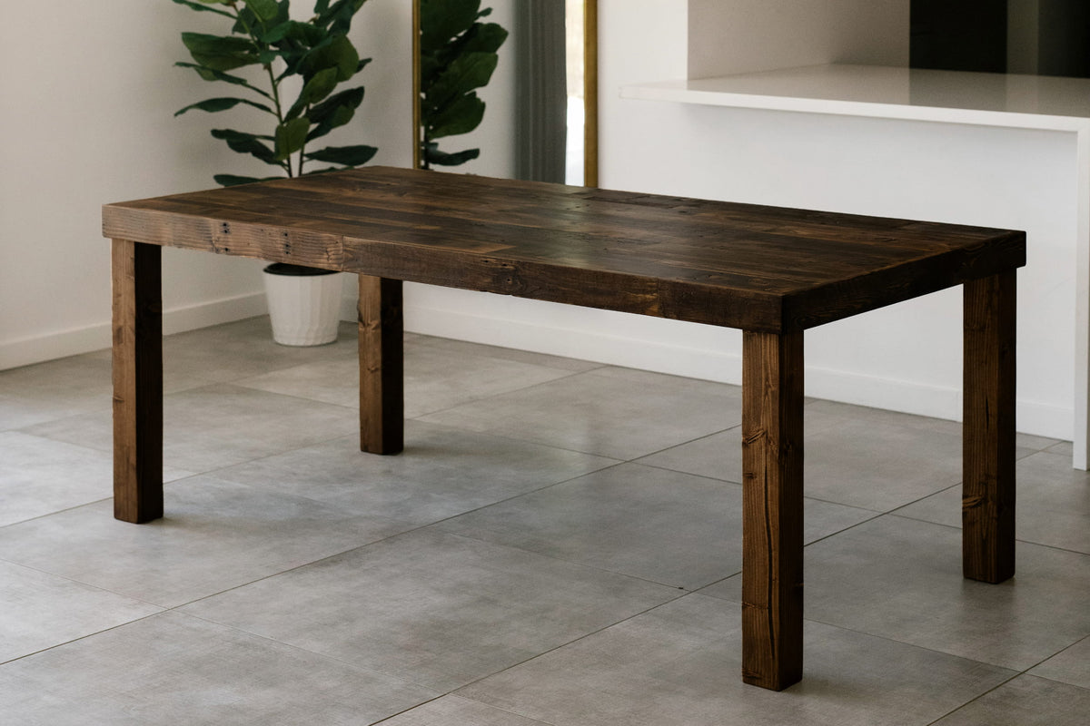 This handcrafted dining table features a rich, reclaimed wood rectangular top and four sturdy legs, offering enduring quality. 