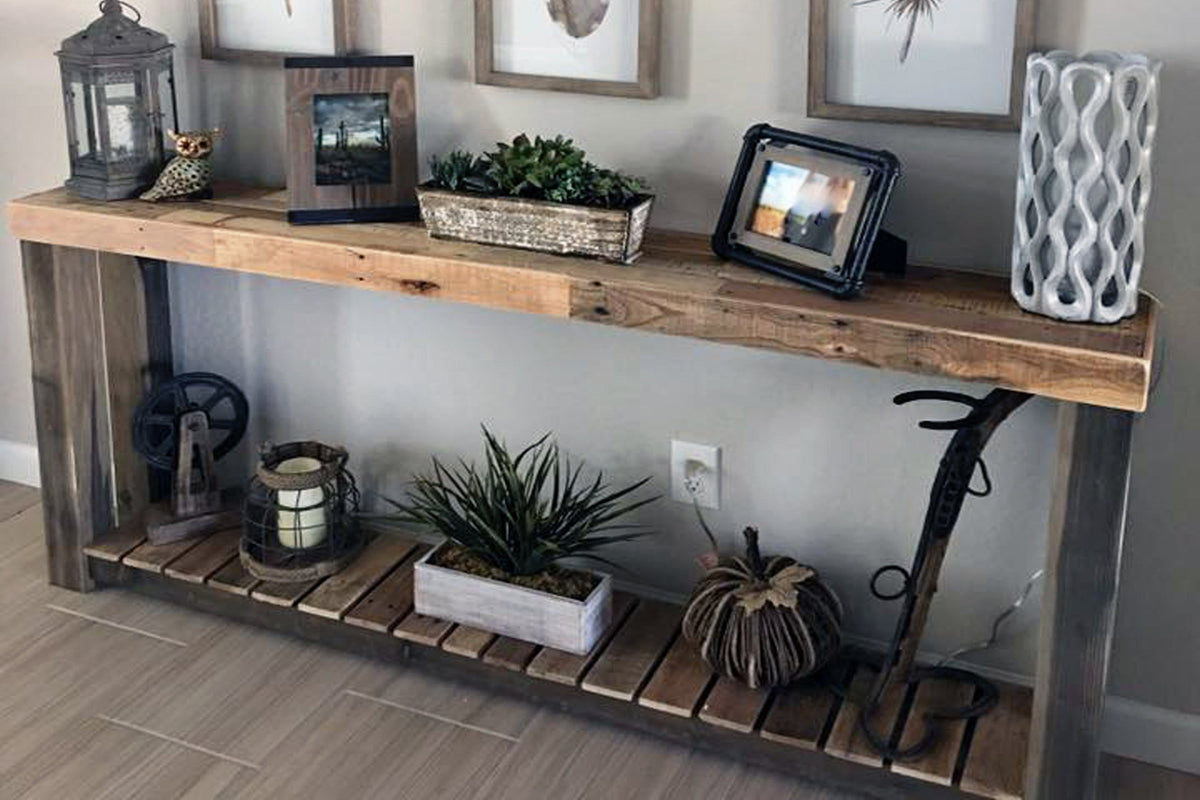 This handcrafted console table, made from sustainably sourced reclaimed wood in Arizona, showcases framed photos, greenery, and artisan decor—eco-friendly reclaimed wood furniture.