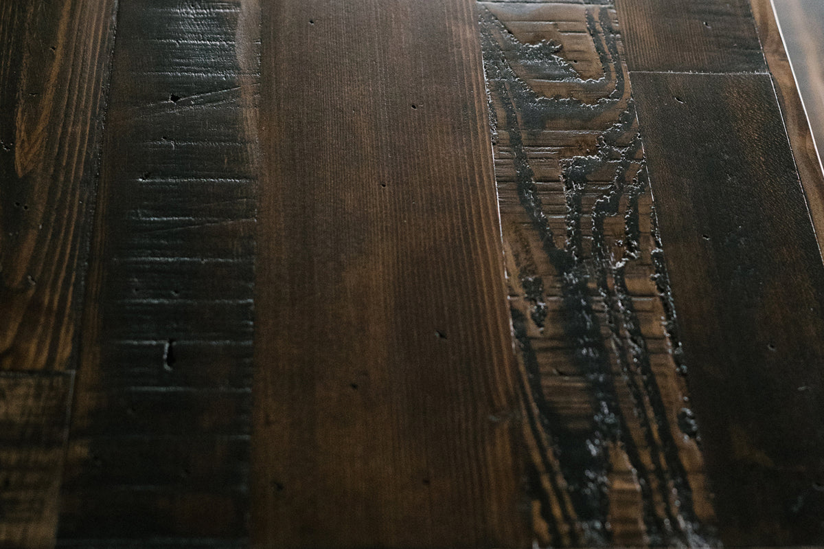Close-up of a sustainable reclaimed wood table, showcasing rich grain, unique scratches, and handcrafted grooves. 