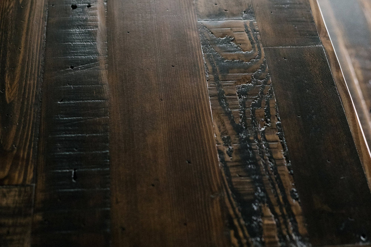 Close-up of a handcrafted reclaimed wood table, featuring a rich dark stain and distinctive grain patterns. Subtle scratches and rustic textures highlight sustainable materials and artisan craftsmanship from Arizona.