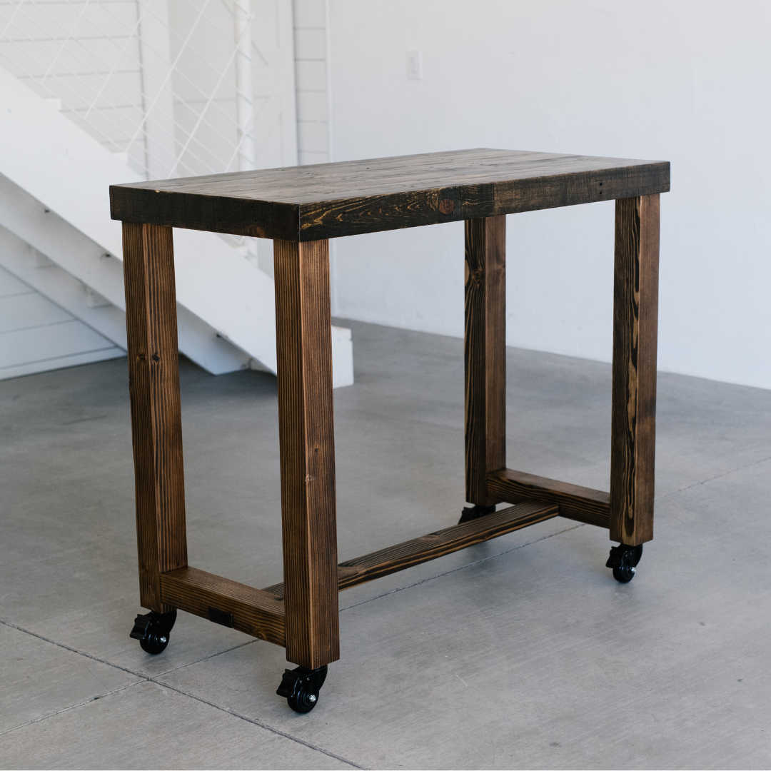 high quality handcrafted bar height wood tables in three different finish colors, photographed in a modern barn with raw concrete flooring and white wood-paneled walls, showcasing Kase Custom's bestselling Sequoia wood high top table