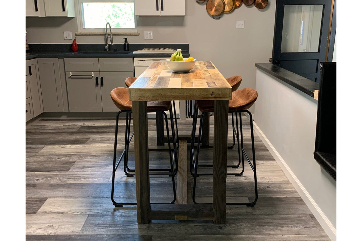 Handcrafted rustic wooden kitchen island made from reclaimed wood, paired with four matching bar-height stools, displayed in a modern kitchen with white cabinetry, gray wood-look flooring, and steel hardware.