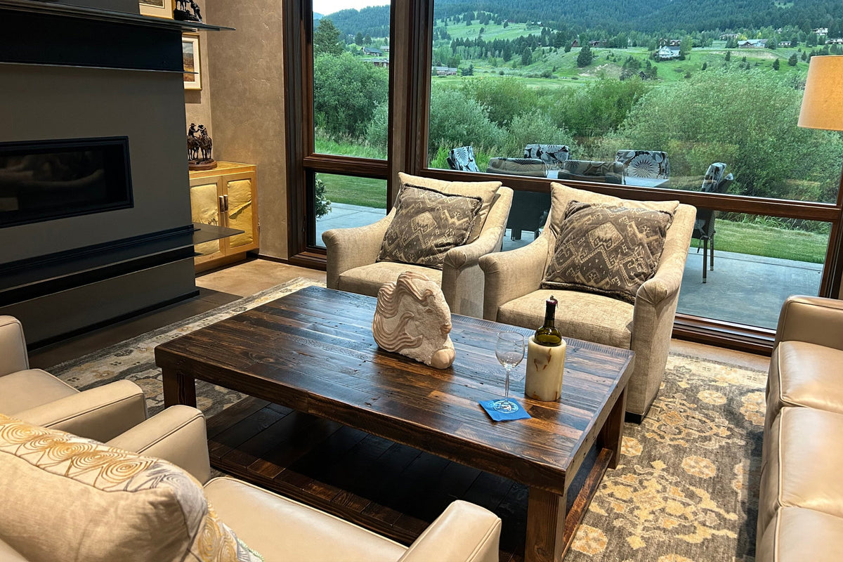 This inviting living room showcases beige armchairs and a rustic reclaimed wood coffee table in Espresso with lower shelf—expertly handcrafted in Arizona—set by expansive windows.