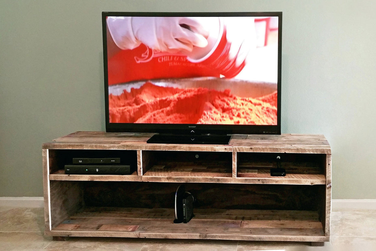 A flat-screen TV sits atop a handcrafted reclaimed wood media console with open shelving and cubby storage, made in Arizona.