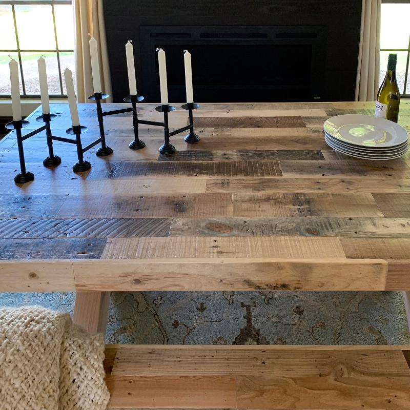 reclaimed wood dining table with candles and plates on it