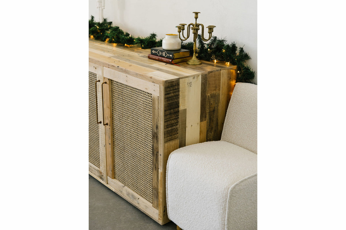 This handcrafted reclaimed wood sideboard features artisan cane doors, highlighting sustainable craftsmanship and enduring quality. Accented with greenery, string lights, and decor, it's a standout in reclaimed wood furniture.
