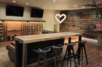 Home theater bar table: Sequoia reclaimed wood bar height table in Natural, behind a row of leather theater seats with four bar stools.