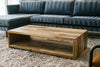 Waterfall reclaimed wood coffee table in front of blue velvet sofa