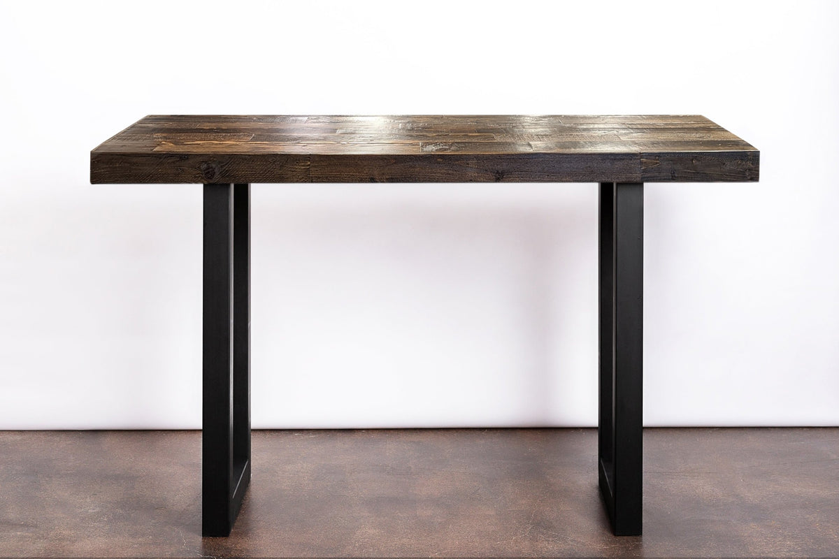 This handcrafted Arizona reclaimed wood table showcases a dark, rustic reclaimed wood top and sleek black steel U-legs. This sustainable reclaimed wood furniture offers enduring style.